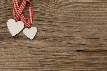 two wood hearts with red stripes on rustic brown wooden background with free space for text
