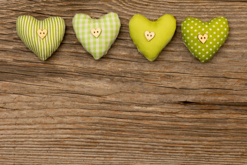four green fabric hearts on rustic brown wooden background with free space for text below