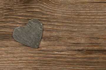 gray slate heart on rustic brown wooden background with free space for text