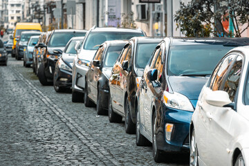 Many Cars parked in row on street in city in sunny summer day. ecological problem - air pollution.