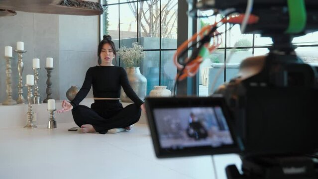 Woman beauty blogger is talking, sits cross-legged, participating yoga in video conference, remotely negotiating with clients, counting. Video tutorial for work or study