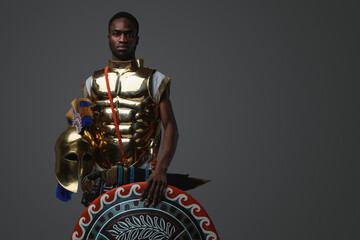 Shot of ancient greek soldier of african ethnic with shield and golden armor.