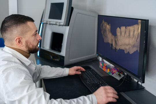 Digital dentistry. Man working with digital scan in modern dentistry. Dental prosthesis on a computer scanner. The dental image is displayed on the computer screen.