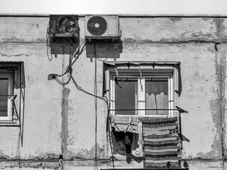 Old worn out communist apartment buliding in Bucharest, Romania. Old clothes laundry left to dry on the balcony. Vintage black and white photography.