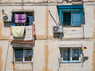 Fototapeta na wymiar Old worn out communist apartment bulding in Bucharest, Romania. Old clothes laundry left to dry on the balcony.
