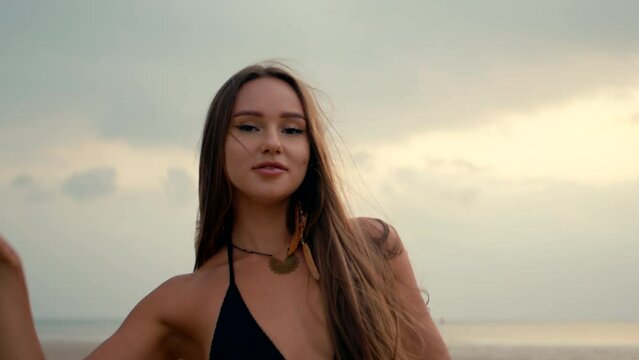 beautiful girl with long straight hair dancing on the beach, watching the sunset