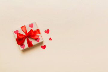 Top view photo of valentine day decorations gift box with red ribbon bow on colored background....