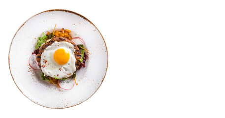 Tasty beef cutlet with fried eggs and onion in a plate on white background. Top view, text space