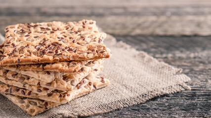 Crispy crackers with sunflower seeds and sesame on rustic background. Text space