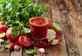 Tomato sauce and ingredients on an old wooden table.