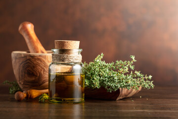 Bottle of thyme essential oil with fresh thyme.