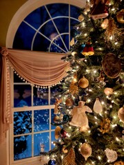Vertical shot of the beautiful Christmas tree in front of a window with a winter scene outside