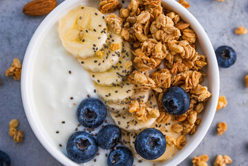 Healthy breakfast. Bowl of greek yogurt with oat granola, fruits, nuts and chia seeds. Top view. Close up
