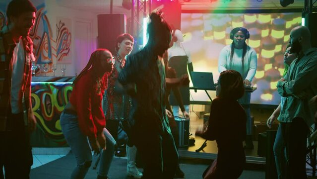 Funky people starting dance battle at party, preparing to show off cool moves on dance floor with friends. Persons having fun with breakdance battle jumping around at discotheque. Handheld shot.