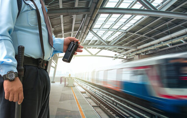 Fototapeta premium Professional security guard hand holding cb walkie-talkie radio in electric train station
