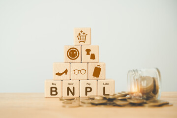 wood block with icon BNPL with online shopping icons blurred coins. Buy now pay later online shopping concept