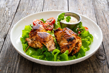Wrapped chicken breasts filled with mozzarella cheese, spinach and tomato sauce served with green vegetables on wooden table
