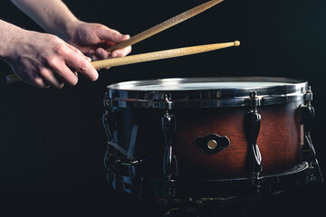 Drummer using drum sticks hitting snare drum with splashing water.