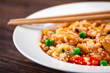 Asian food - chicken nuggets, rice, stir fried vegetables, soy sauce and mushrooms on wooden table 