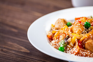 Asian food - chicken nuggets, rice, stir fried vegetables, soy sauce and mushrooms on wooden table 