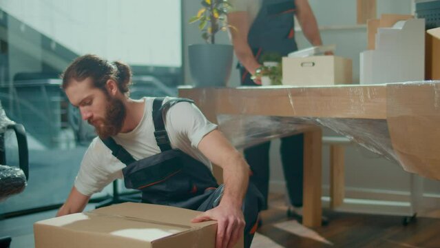 Employee Worker Sealing Cardboard Box Using Duct Tape Machine. Professional Packing and Unpacking Services. Packing and Preparation for Moving. Packing Supplies and Materials