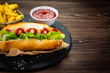 Hot dog, French fries and ketchup on wooden table
