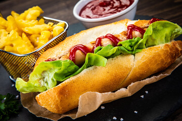 Hot dog, French fries and ketchup on wooden table
