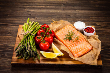 Fresh raw salmon steaks with fresh vegetables on cutting board
