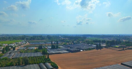 Beautiful bird's eye view of a land with greenhouses and lush trees in a village