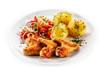 Barbecued chicken wings with boiled potatoes and tomato salad on white background