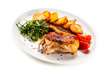 Barbecued chicken thigh with fried potatoes, arugula and tomatoes on white background