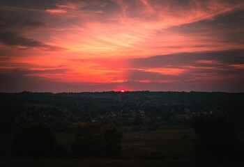 Bright sunset shining over the small town in the red and pink sky behind the horizon