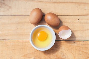 A yellow egg yolk in a bowl on wood table - obrazy, fototapety, plakaty