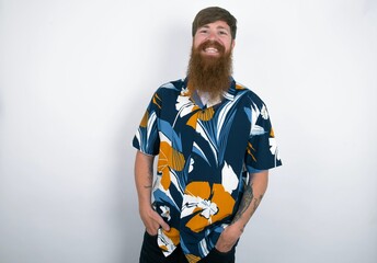 Portrait of successful red haired man wearing printed shirt over white studio background, smiling...