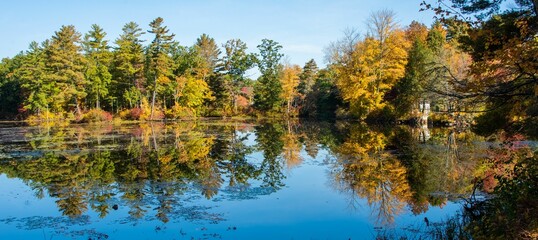 Panoramic shot of a pond reflecting an autumn forest, Old Sturbridge Village, USA