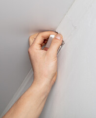 A worker installs a skirting board on the ceiling
