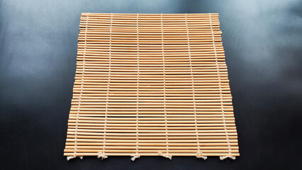 Asian bamboo mat and napkin from yellow bamboo on black surface. Background, texture, frame, copy...