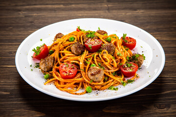 Spaghetti with meatballs in tomato sauce on wooden table
