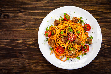 Spaghetti with meatballs in tomato sauce on wooden table
