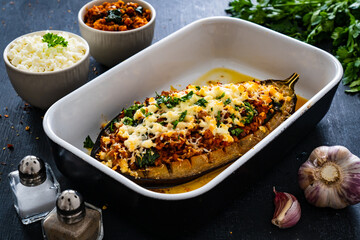 Roasted aubergine stuffed with minced meat and cheese on wooden table
