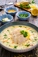 Greek lemon creamy soup with cooked chicken breast on wooden table

