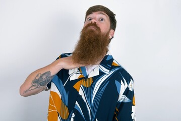 red haired man wearing printed shirt over white studio background cutting throat with hand as...