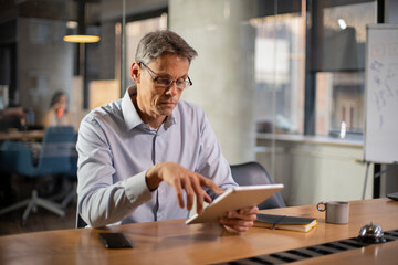 Fototapeta premium Portrait of businessman in office. Man using digital tablet. Businessman having video call.