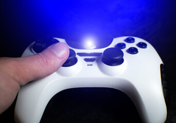 Man is playing computer games on Black and White modern wireless Gamepad and pushing buttons and analogs, close up.