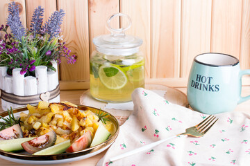 green tea with lime and mint in a glass jar with a plate of country fried potatoes. Homemade food, lunch