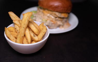 Fresh tasty burger and french fries on black table.