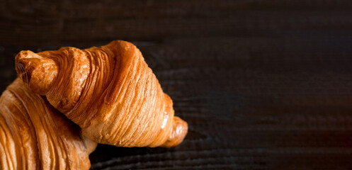 Two croissants on a wooden cutting board. Rustic dark table. Food banner. Tasty fresh croissant, jam, orange juice. Continental breakfast served with freshly baked pastry. Close up view, Good morning