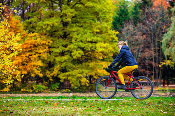 Fototapeta na wymiar Woman riding bicycle in city park 
