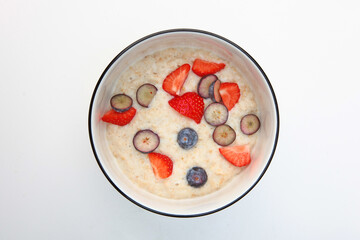 Oatmeal porridge with strawberries and blueberries. Healthy breakfast. Flat lay. Top view. Copy space. Isolated object.