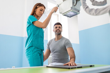 Obraz premium Female doctor taking hand X-ray of man in hospital. Radiologist is operating X-ray machine. Man undergoing treatment in clinic.